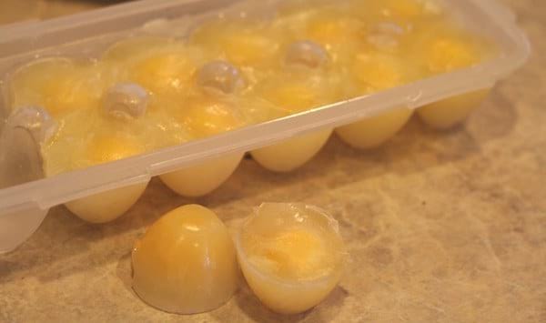 Una bandeja de cubitos de hielo con huevos para congelar.