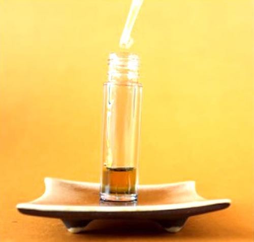 Un gotero que vierte los aceites esenciales en un frasco, para hacer un suero antiarrugas.