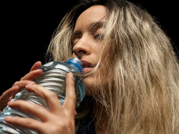 Una mujer bebe agua de una botella.
