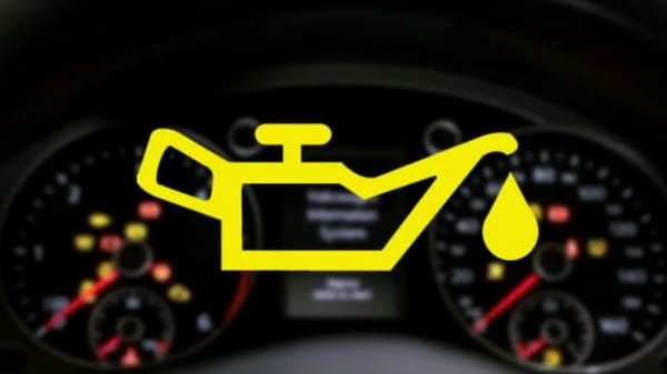 Una luz amarilla de advertencia del nivel de aceite del motor frente al panel de instrumentos.
